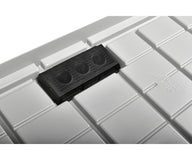 Close-up of a black drain screen with three circular openings on a white, textured grow tray.