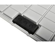 Close-up of a black plastic insert with three circular vents set into a grey, grid-patterned surface.