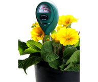Yellow primroses with green leaves in a black pot, featuring a green two-way moisture and pH meter.
