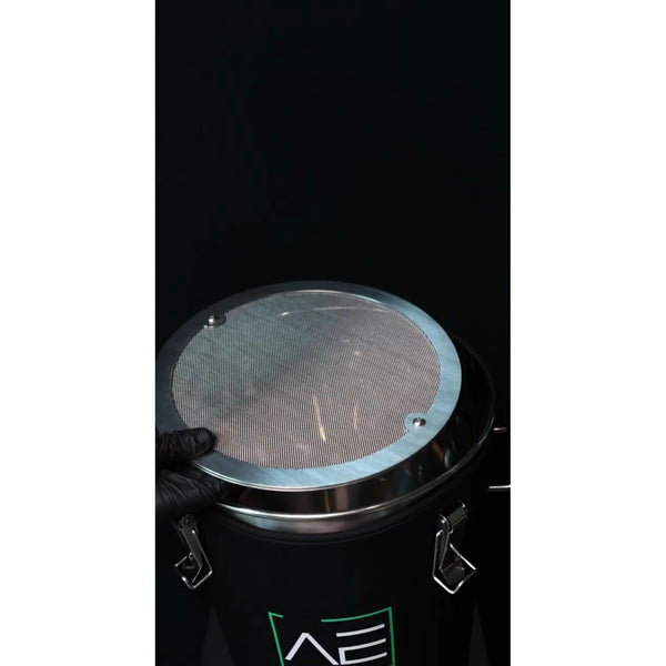 Black hash washer with stainless steel lid. A person in a black glove holds the lid.
