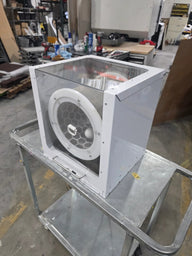 A white, clear-top extraction tumbler with a white circular grate on a silver metal cart in a workshop.