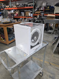 White mini extraction tumbler with clear lid on a silver cart in a warehouse.