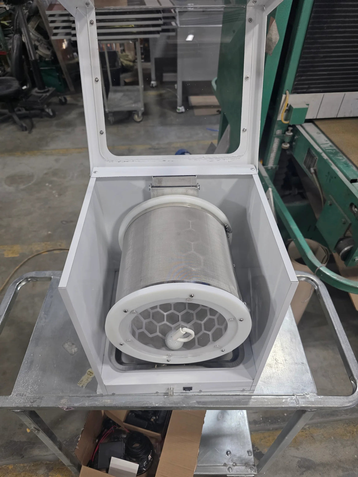 Amped Mini Extraction Tumbler with mesh cylinder, hex pattern filter, and clear lid, on a metal cart.