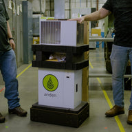 Man in blue jeans with hand on white Anden humidifier box, another man on left.