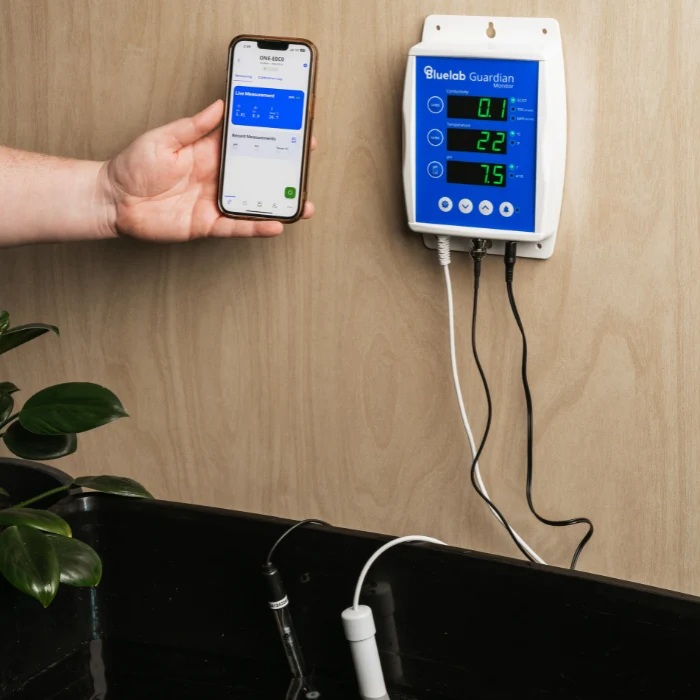 Bluelab Guardian Monitor Wi-Fi with phone displaying conductivity, temperature, and pH readings.
