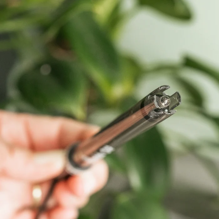 Close-up of a Bluelab ORP probe held by a hand against a blurred green plant background.