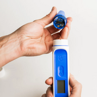 Person holds blue probe with circuitry, above white and blue meter on white background.