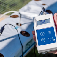 Bluelab Combo Meter with pH 5.8 reading, held over a hydroponic system.