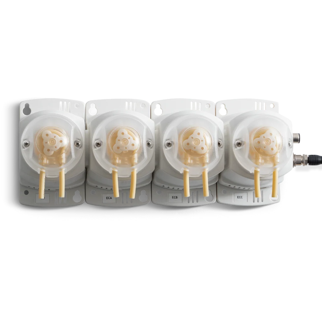 Four white Bluelab PeriPod M4 peristaltic dosing pumps with clear covers and beige tubing, mounted on a dark background.