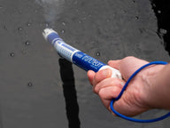 Hand holding Bluelab Truncheon nutrient meter in dark water with bubbles.