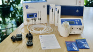 Bluelab pH Controller Wi-Fi kit with probes, tubes, power adapter, and calibration solutions on a wooden table.