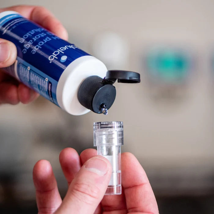 Hands pour Bluelab pH probe storage solution into a clear vial.