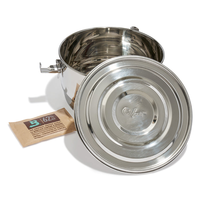Stainless steel CVault container with lid off, next to a Boveda 62% humidity pack.