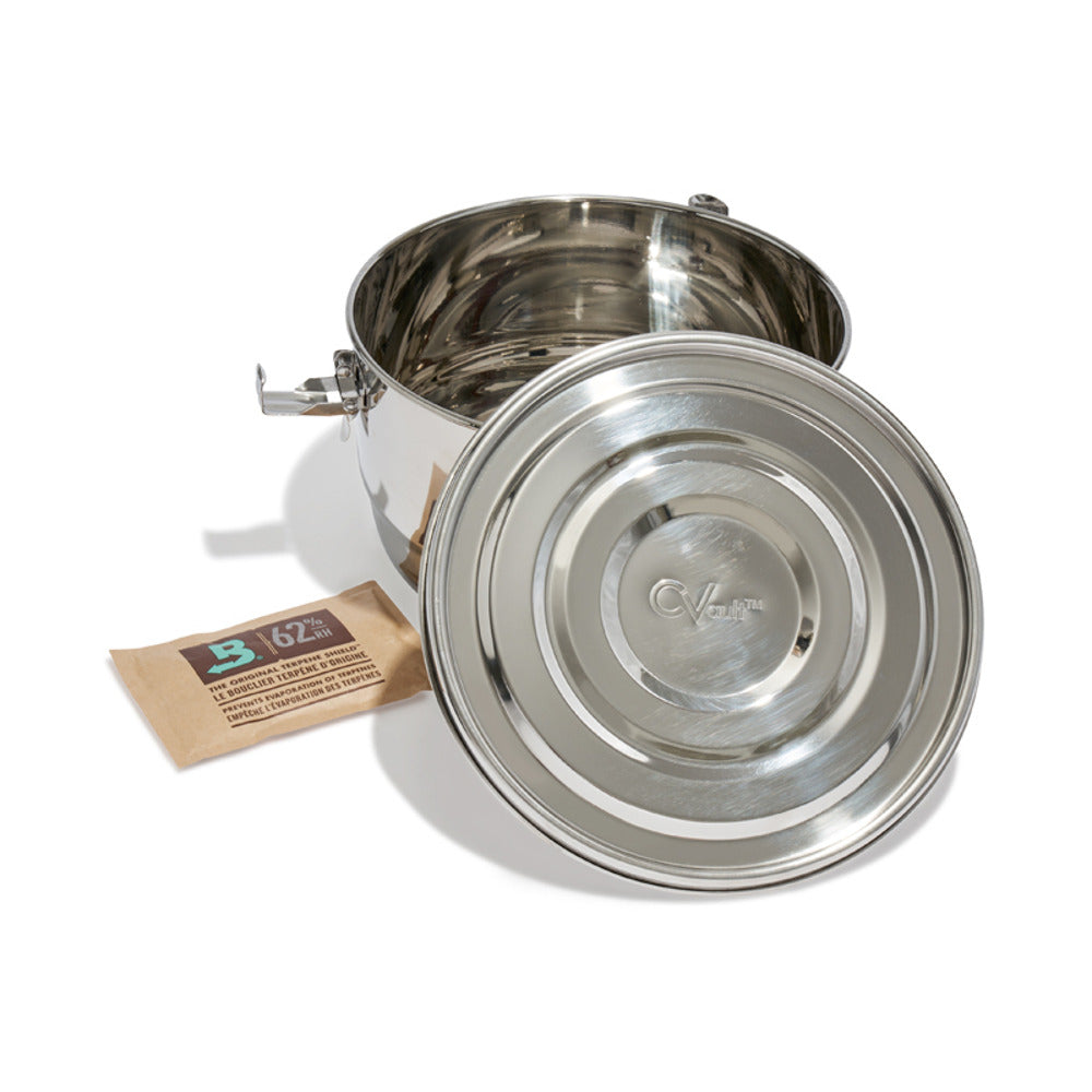 Stainless steel CVault container with lid off, next to a Boveda 62% humidity pack.