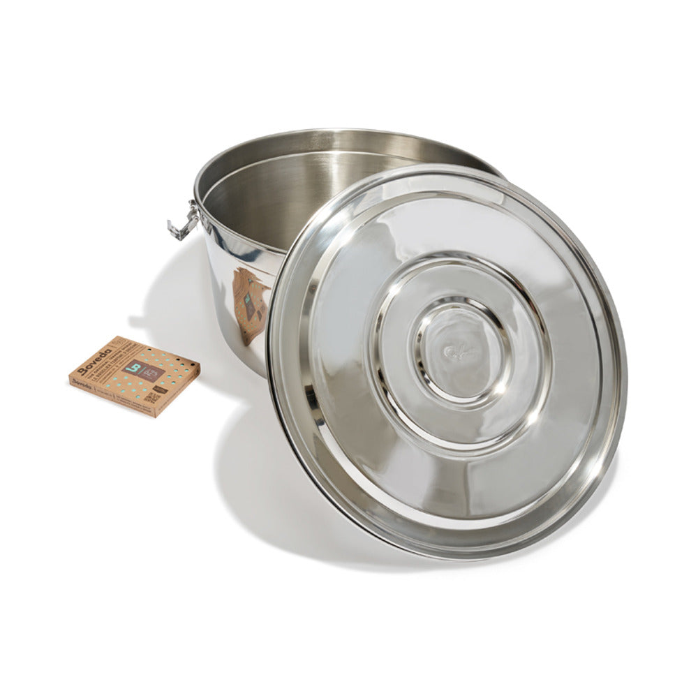 Stainless steel CVault storage container with lid open, next to Boveda humidity pack.