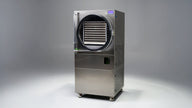 Commercial freeze dryer with stainless steel exterior, transparent door showing shelves, and a digital display.