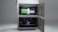 Two-door industrial cabinet revealing vacuum pump and compressors.
