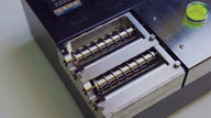 Close-up of industrial machine with two sets of ribbed rollers, metal casing, and digital display.