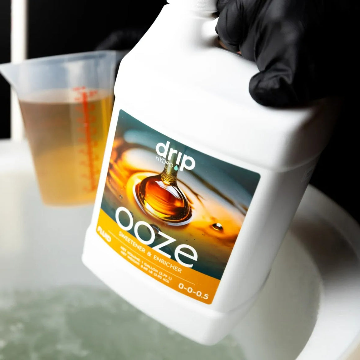 Drip Hydro Ooze bottle, sweetener & enricher, 0-0-0.5 NPK, near measuring cup.