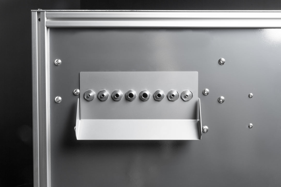 Silver machine panel with multiple metal nozzles and a tray.