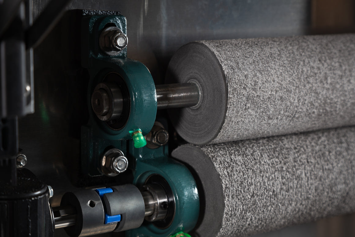 Close-up of industrial rollers and bearing block on a machine.