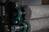 Close-up of industrial rollers and bearing block on a machine.