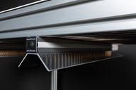 Close-up of a silver metal frame with ribbed texture beneath, and a black rectangular label with 