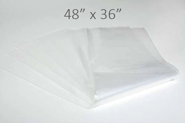 Stack of 48" x 36" clear plastic tote liners on a white surface.