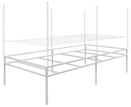 A white metal trellis support system with two wire shelves and four vertical posts with pegs.