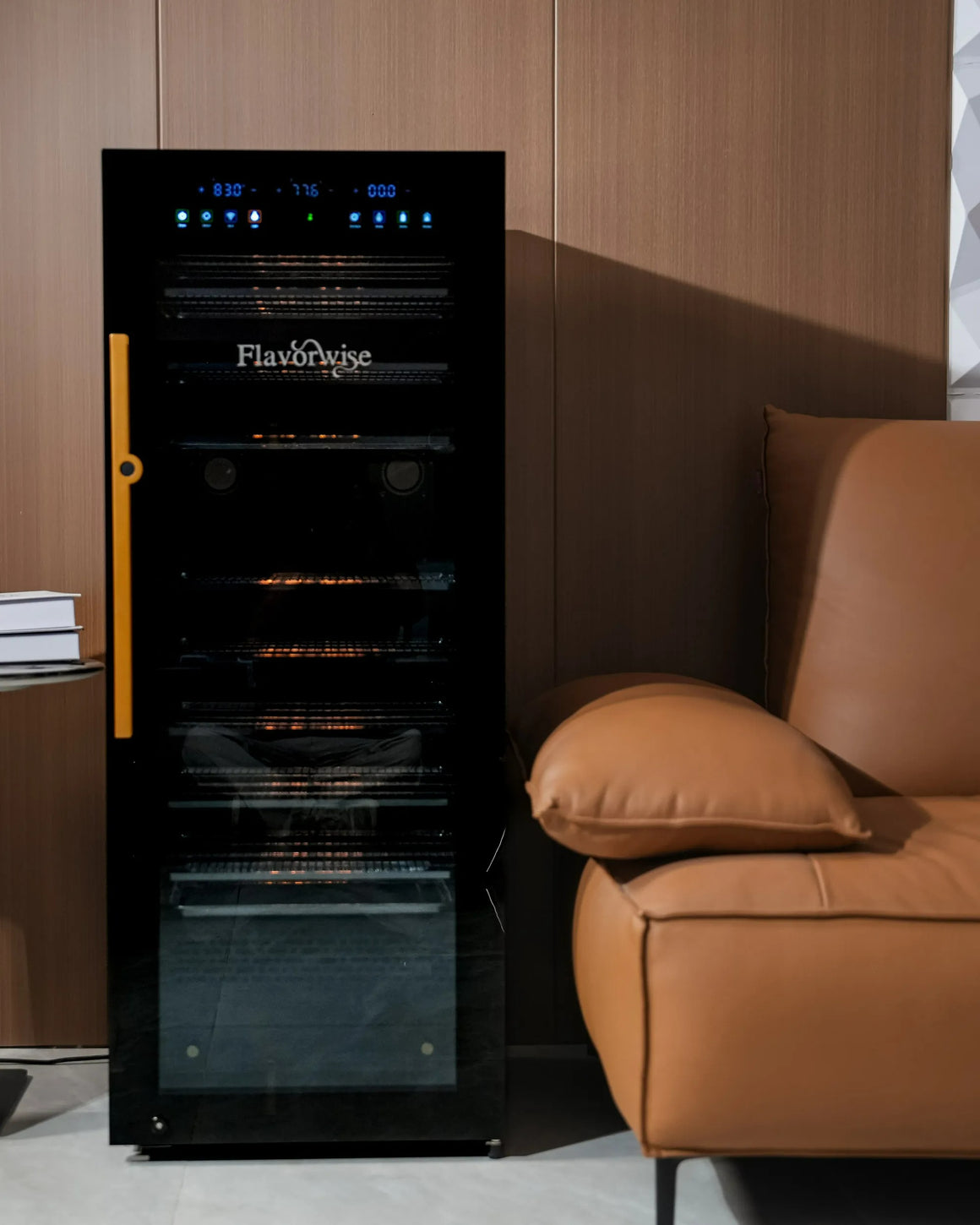 Flavorwise smart drying & curing cabinet with glass door and digital display, next to a brown leather sofa.