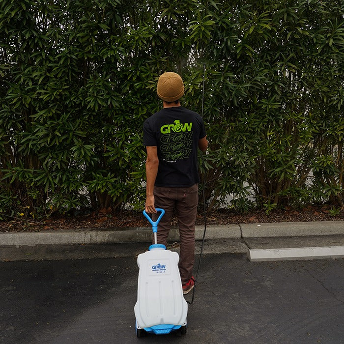 Man with GROW t-shirt sprays bushes from a white and blue 20L electric sprayer.