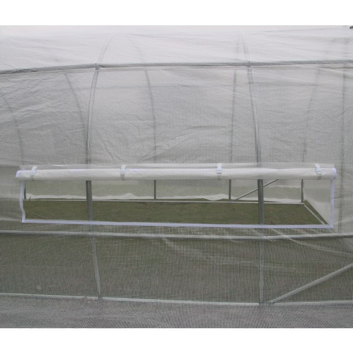 Greenhouse with rolled-up clear window, showcasing green grass inside.