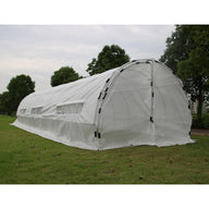White hoop house greenhouse with roll-up windows on grassy field.