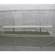 A close-up of a white greenhouse with a rolled-up vent window and view of green grass inside.