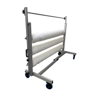 A cannabis trellis netting system with three rolls of white netting on a mobile aluminum frame with blue wheels.