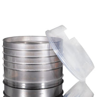 Stack of stainless steel sieves with a clear plastic lid for soil analysis or laboratory use.