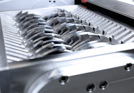 Close-up of a shredder's sharp, interlocking metal blades in a metallic housing.