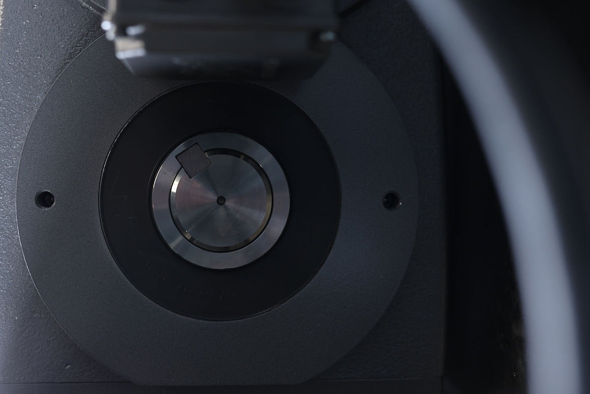 Close-up of a metal shredder aperture with circular cutting mechanism and engraved serial numbers.