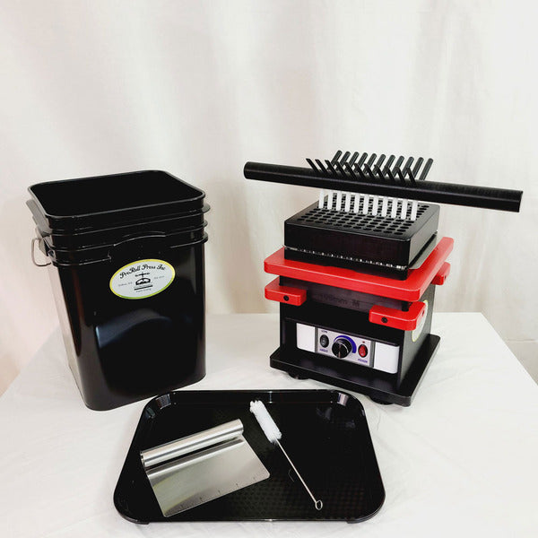 Black bucket, red and black pill press machine, black tray with scraper and brush.