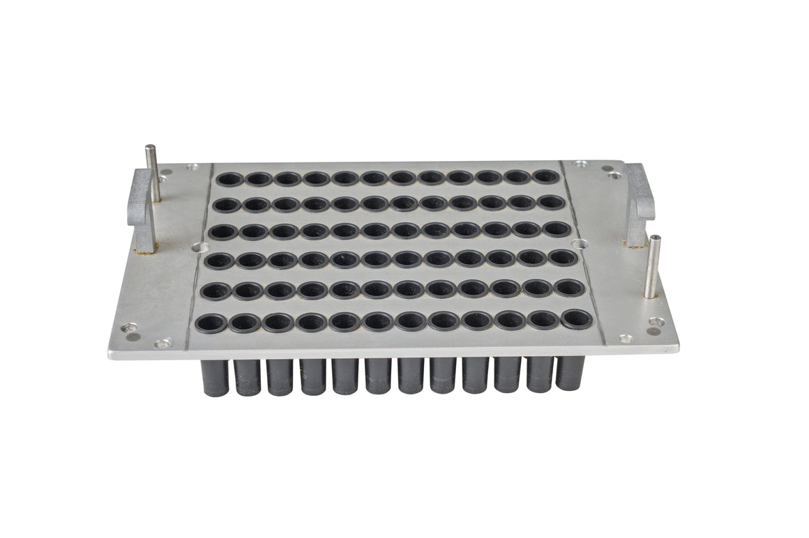 Close-up view of an aluminum capsule filling tray with rows of black rubber gaskets to hold capsules.