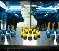Robotic arm sorts pre-rolls on a metal surface with blue and yellow holders.