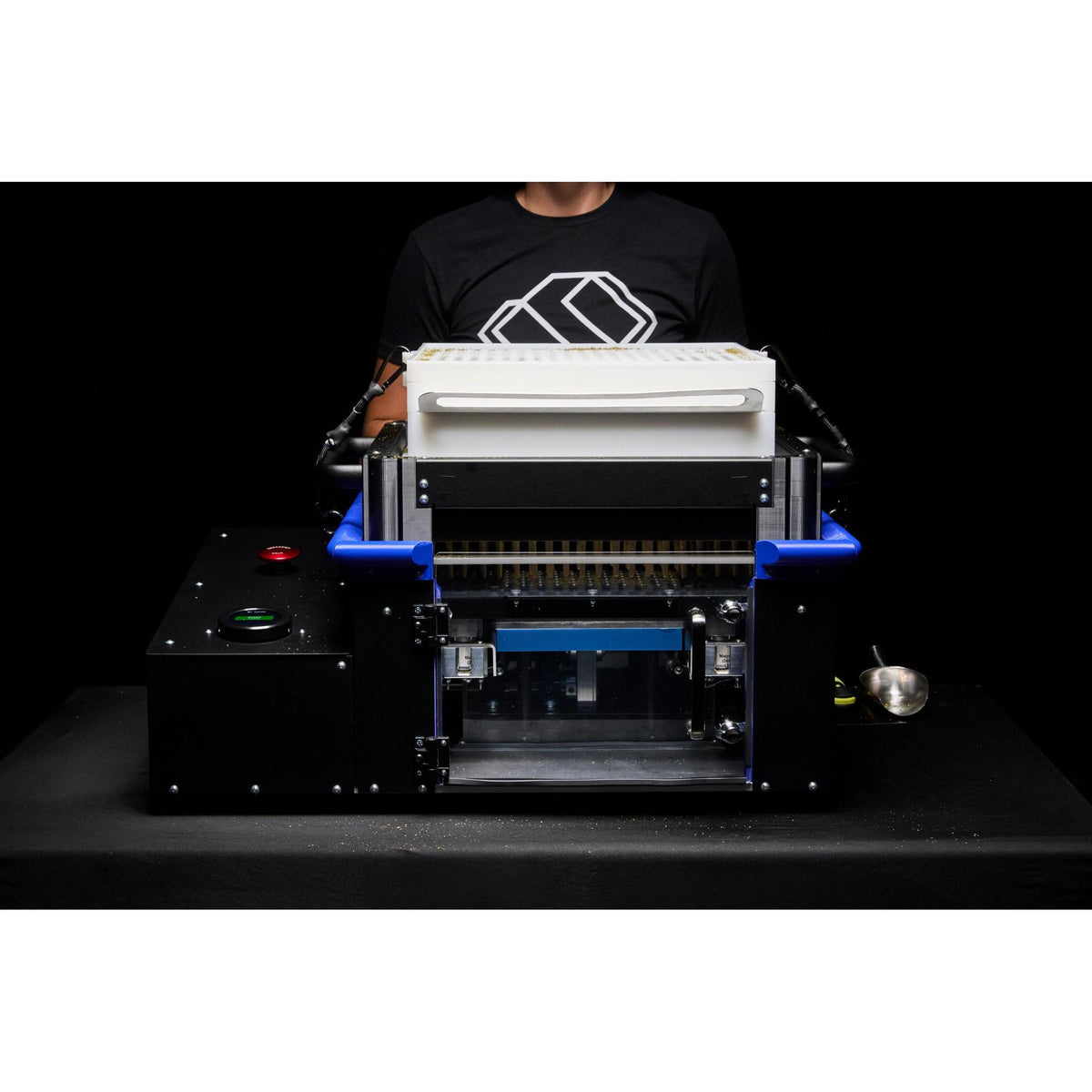 Robotic sorting machine with white top hopper and blue arms against black background.