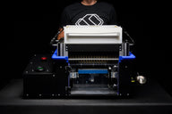 Robotic sorting machine with white top hopper and blue arms against black background.