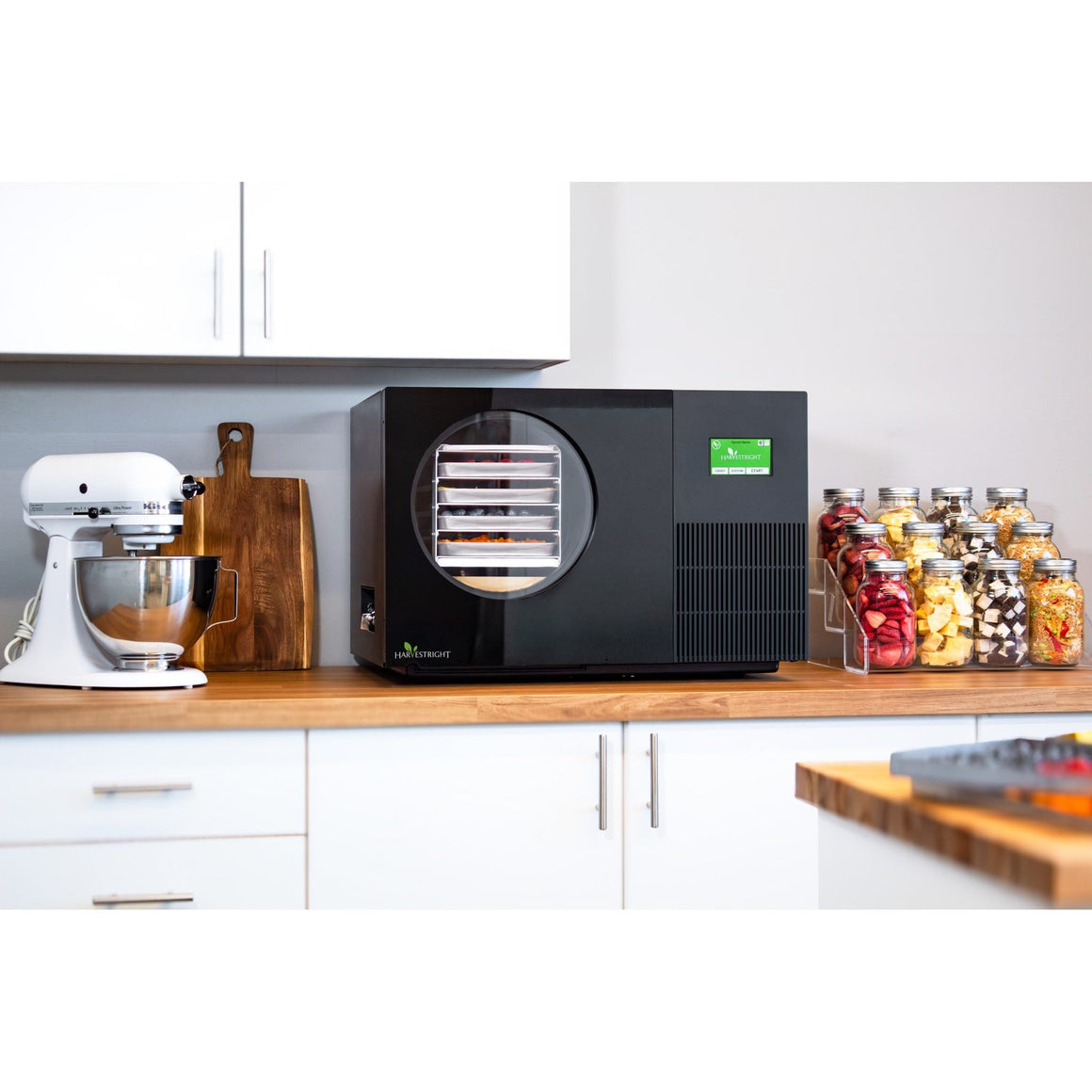 Black Countertop 360 freeze dryer on a kitchen counter next to a stand mixer and jars of freeze-dried fruit