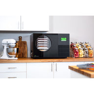 Black Countertop 360 freeze dryer on a kitchen counter next to a stand mixer and jars of freeze-dried fruit