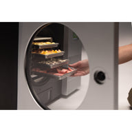 Hand reaching a tray of freeze-dried food inside the chamber of the stainless steel Countertop 360
