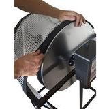 Hands adjusting mesh netting on a rotating drum of a tumble trimmer.